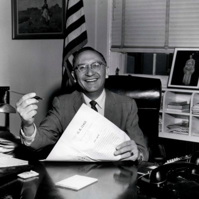 Ben Reifel sitting at his desk, about to sign a document.