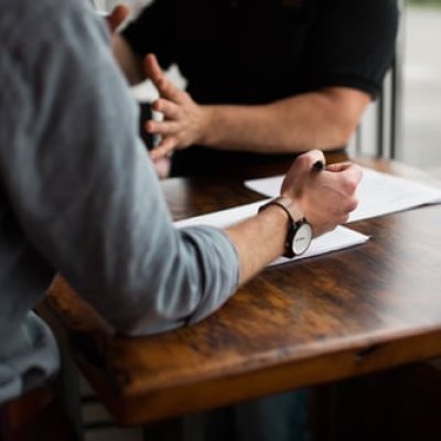 two people writing on paper on brown wooden table