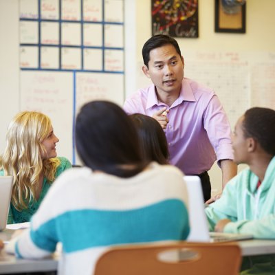 High school teacher talking to students around a table.