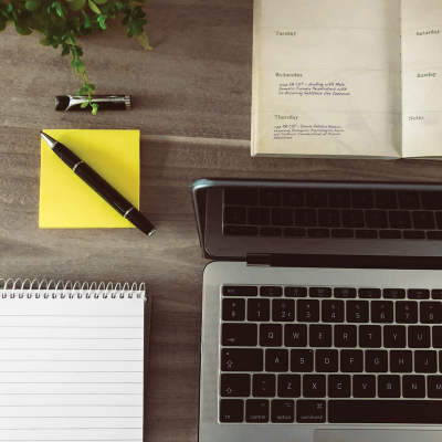 Planner with sticky notes, pen, and the edge of a laptop