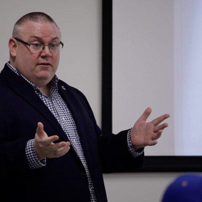 Man in black coat standing and teaching a class