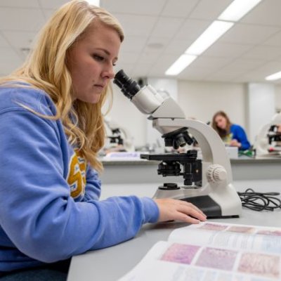 Studying using a microscope and textbook to study 