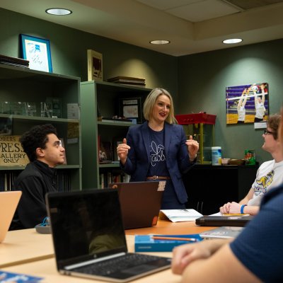 Instructor leading a conversation with a small group of students in a conference room.