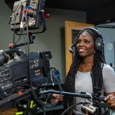 Student operating a large video camera wearing a headset.