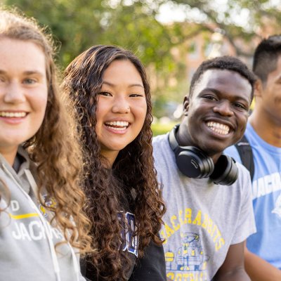 Five students sitting out on the campus green