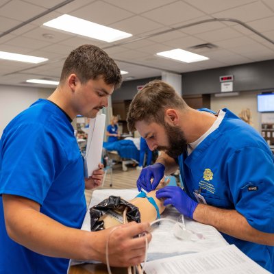 Nursing student and professor working on simulated arm.