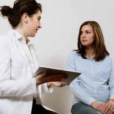 Individual in white coat sharing information with another person.