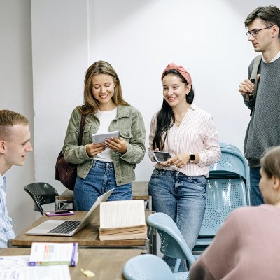 Five students in a classroom talking.