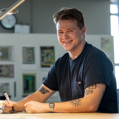 Man sitting by desk smiling at camera.