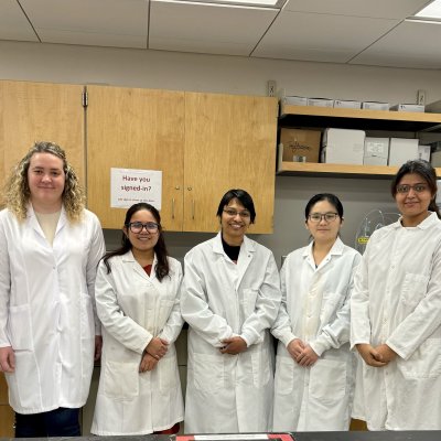 A group image taken with 6 graduate students and their advisor in lab attire inside Alfred lab manufacturing lab.