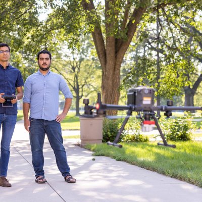 student and faculty flying a drone on the campus green