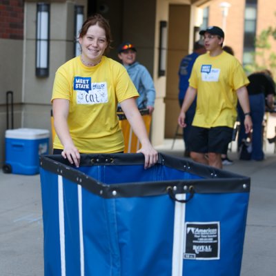 Meet State volunteer pushing a cart and smiling at the camera.