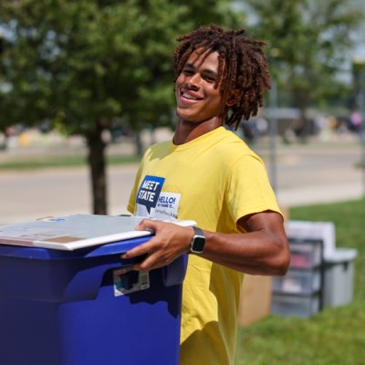 Meet State volunteer smiling at camera and carrying a plastic tub.