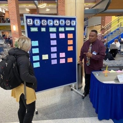 A staff member playing Jeopardy with a student