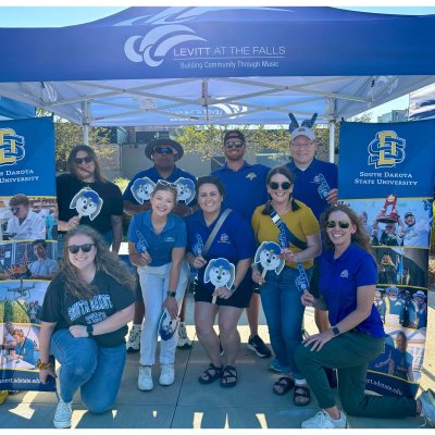 A group of people in SDSU Jackrabbit apparel smiling at the camera