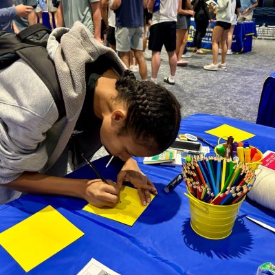 A student writing on a yellow sheet of paper