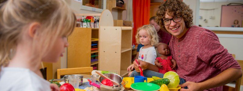 student teacher playing with children in classroom