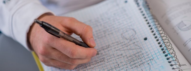 Close up of a person writing in the notebook