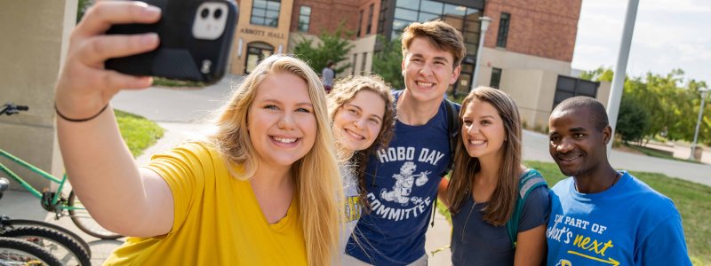 Group of students taking a group photo using a cell phone.