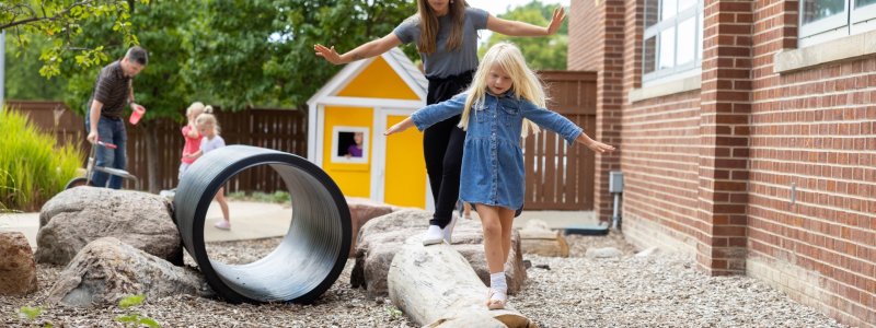 Student teacher and child playing on log