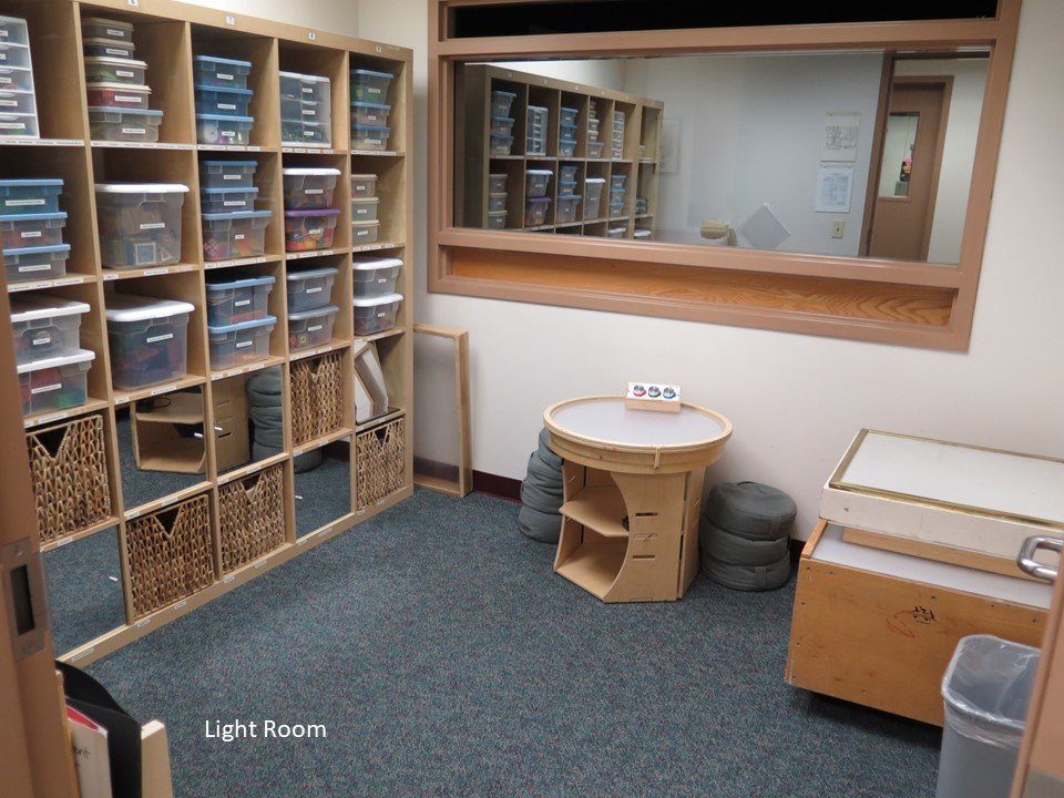 The light room space. There are different styles of light tables as well as shelves holding a variety of materials to be used on a light table.