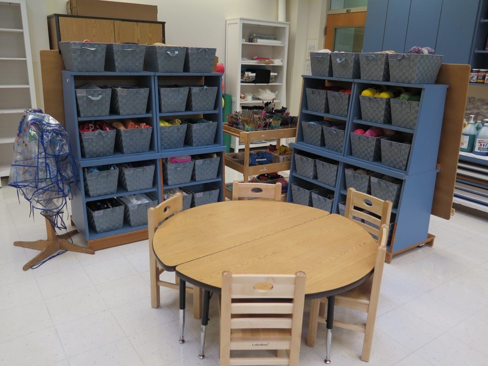 A table next to the fabric and ribbon baskets in the art studio.