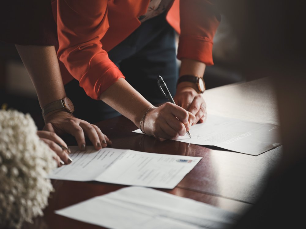 a person signing a document on a table