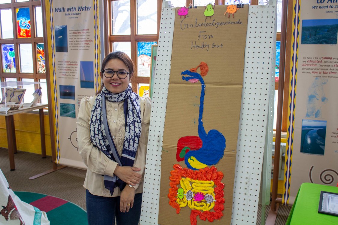 Graduate student Ifra Tun Nur standing near a cardboard model of human digestive system.