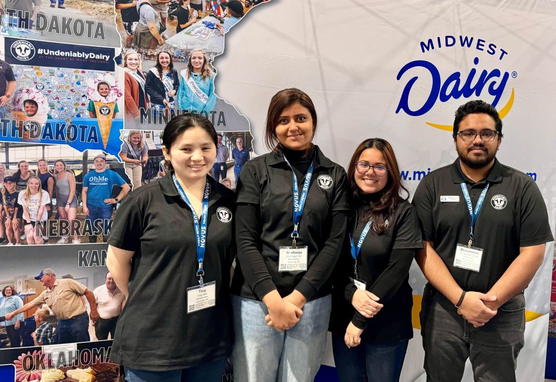 Four graduate student standing Infront of Midwest dairy poster.