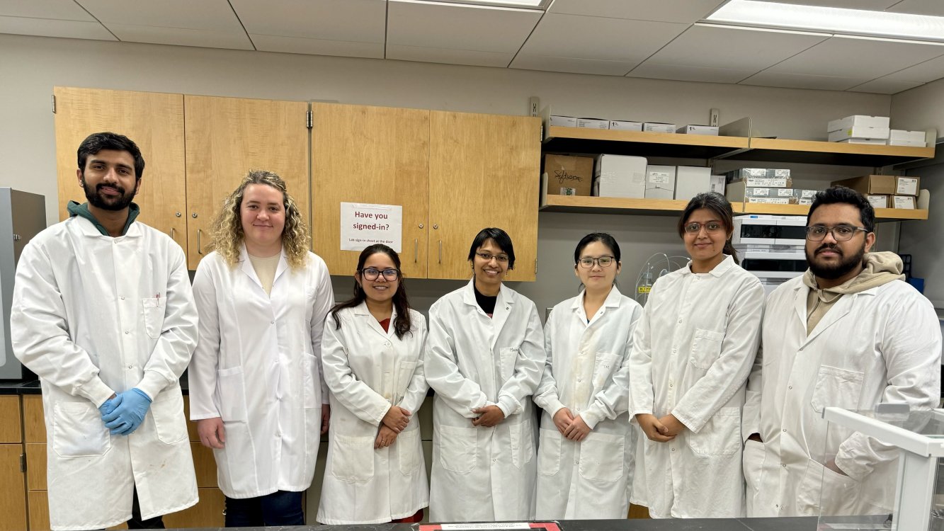 A group image taken with 6 graduate students and their advisor in lab attire inside Alfred lab manufacturing lab.