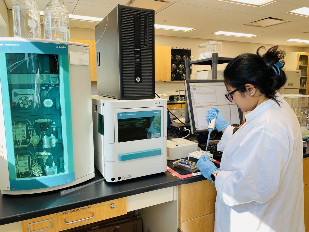 A grad student placing sample in front of an Ion-Chromatography equipment.