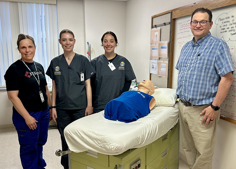 Two respiratory care instructors and two respiratory care students stand around a manikin