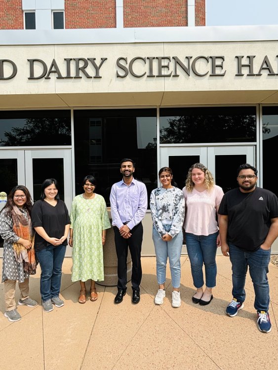 A group image taken with 6 graduate students and their advisor outside Alfred Dairy Science Hall.