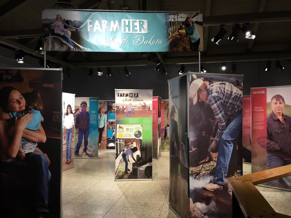 Farm:Her exhibit opening panels and banner, with producer profiles in the background.