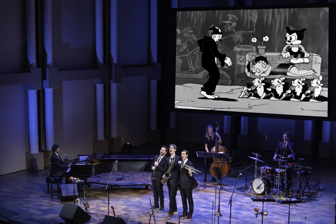 The Queen's Cartoonists perform on stage.