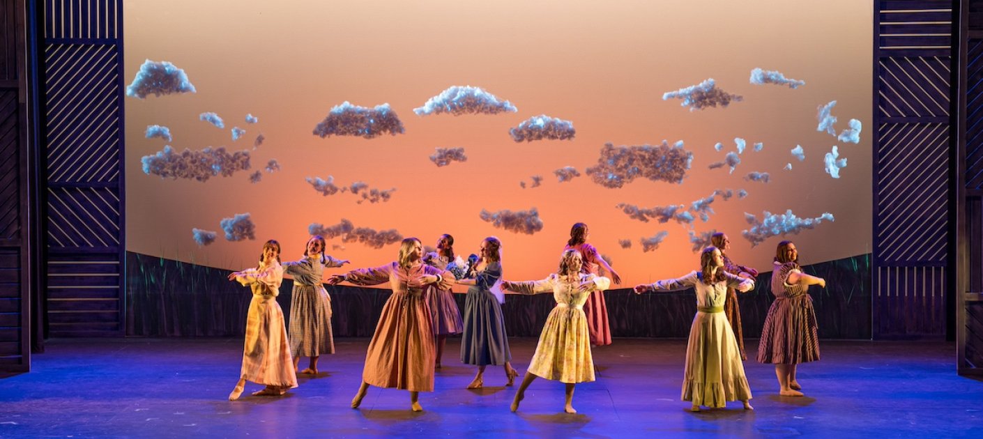 Multiple dancers performing on a blue stage