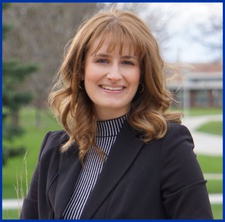 Student's Association College of Arts, Humanities, and Social Sciences senator Madeline Brink sitting on a bench outside smiling