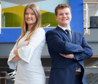 Student's Association President Trinity Peterson and Vice President Hayden Bentz standing in the South Dakota State University Student Union with their backs towards each other, arms crossed, and smiling.
